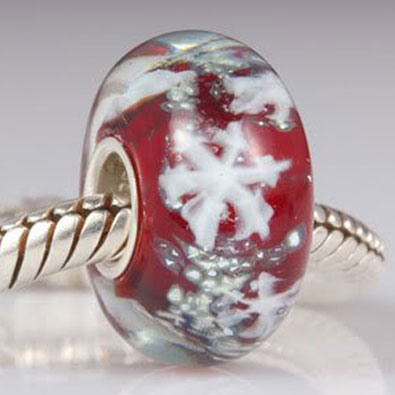a red glass bead with snowflakes